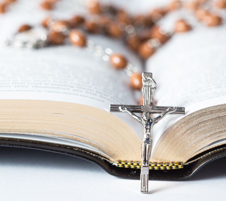 Cross of rosary beads resting against open bible